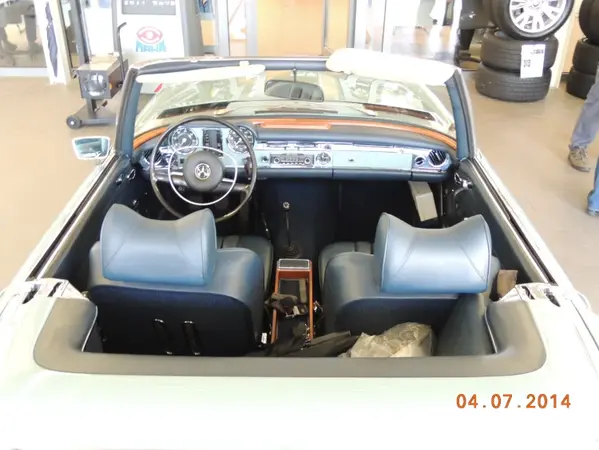 Klassisches Mercedes SL Cabrio mit blauen Ledersitzen und offenem Verdeck im Autohaus.