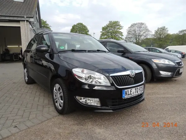 Schwarzer Skoda Fabia Kombi steht auf einem Parkplatz vor einem Autohaus bei Tageslicht.